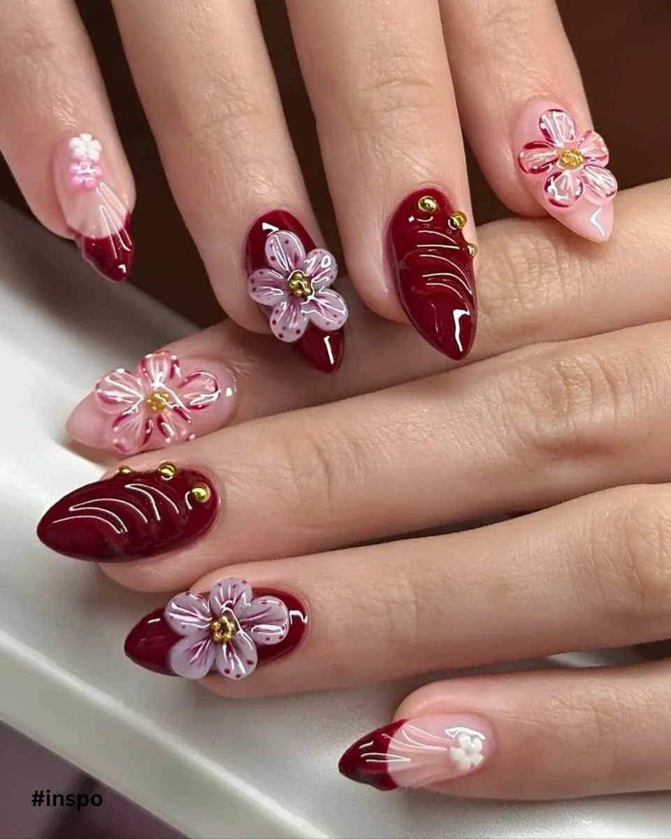Burgundy almond nails with sculpted 3D flowers and pearl accents