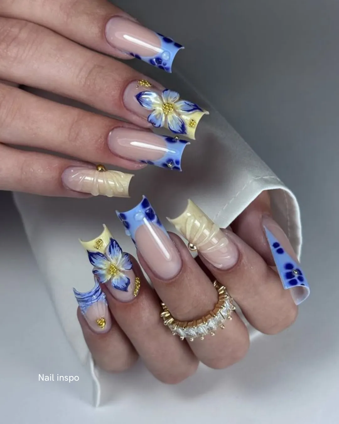 Nude nails with delicate blue painted florals and gold beads