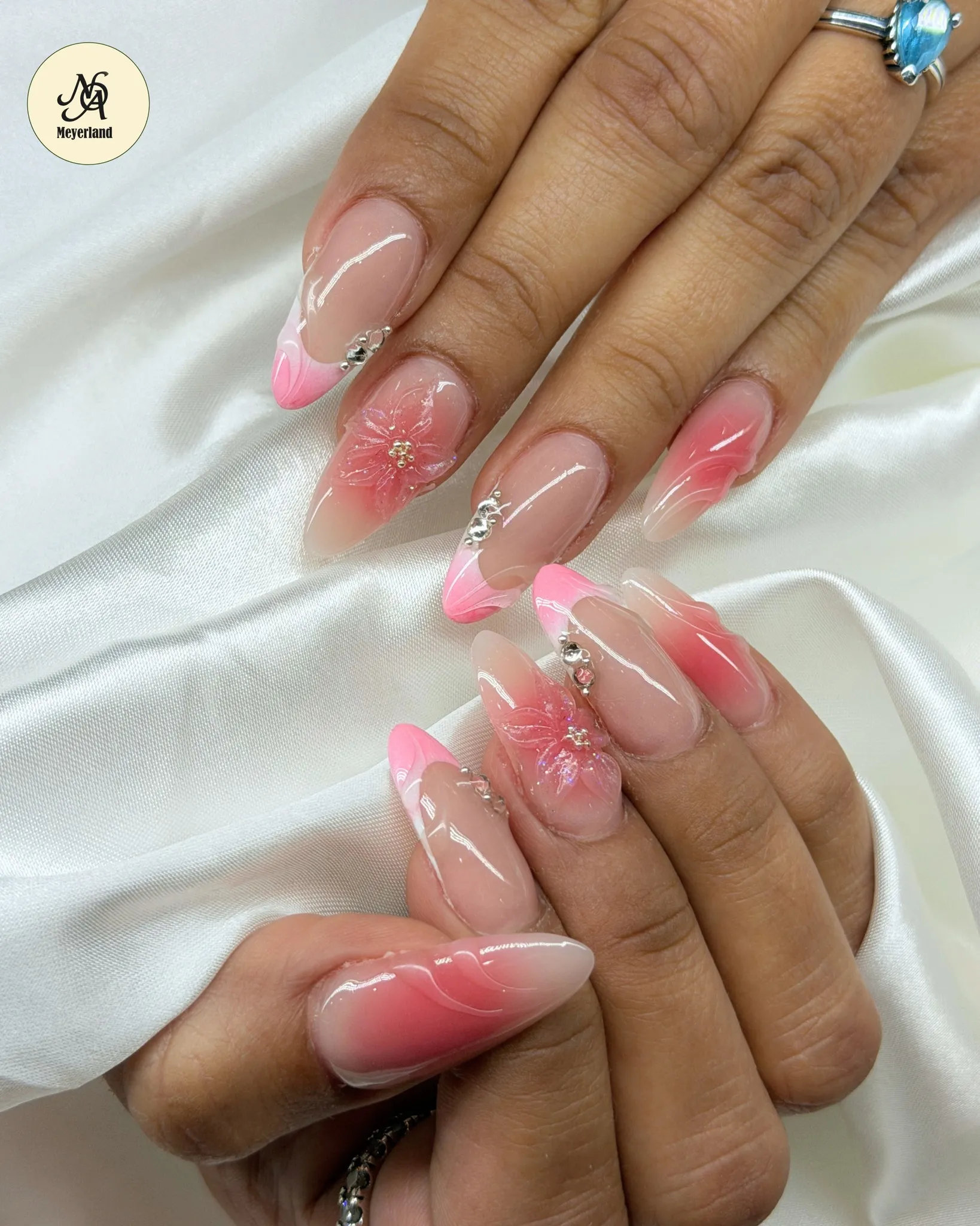 Glossy pink ombré almond nails with delicate 3D floral art by Nails of America Meyerland
