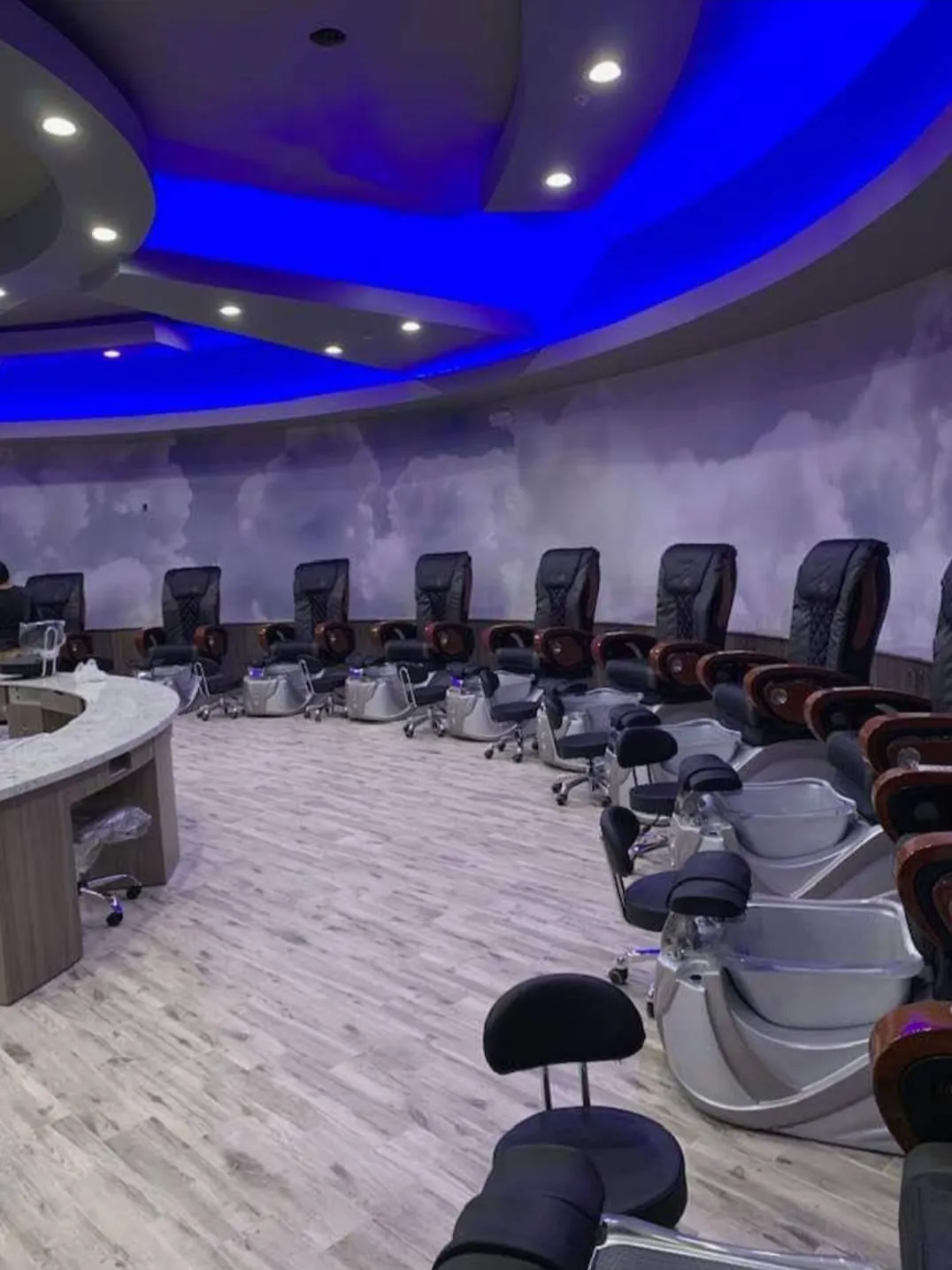 Row of plush massage pedicure thrones under ambient lighting