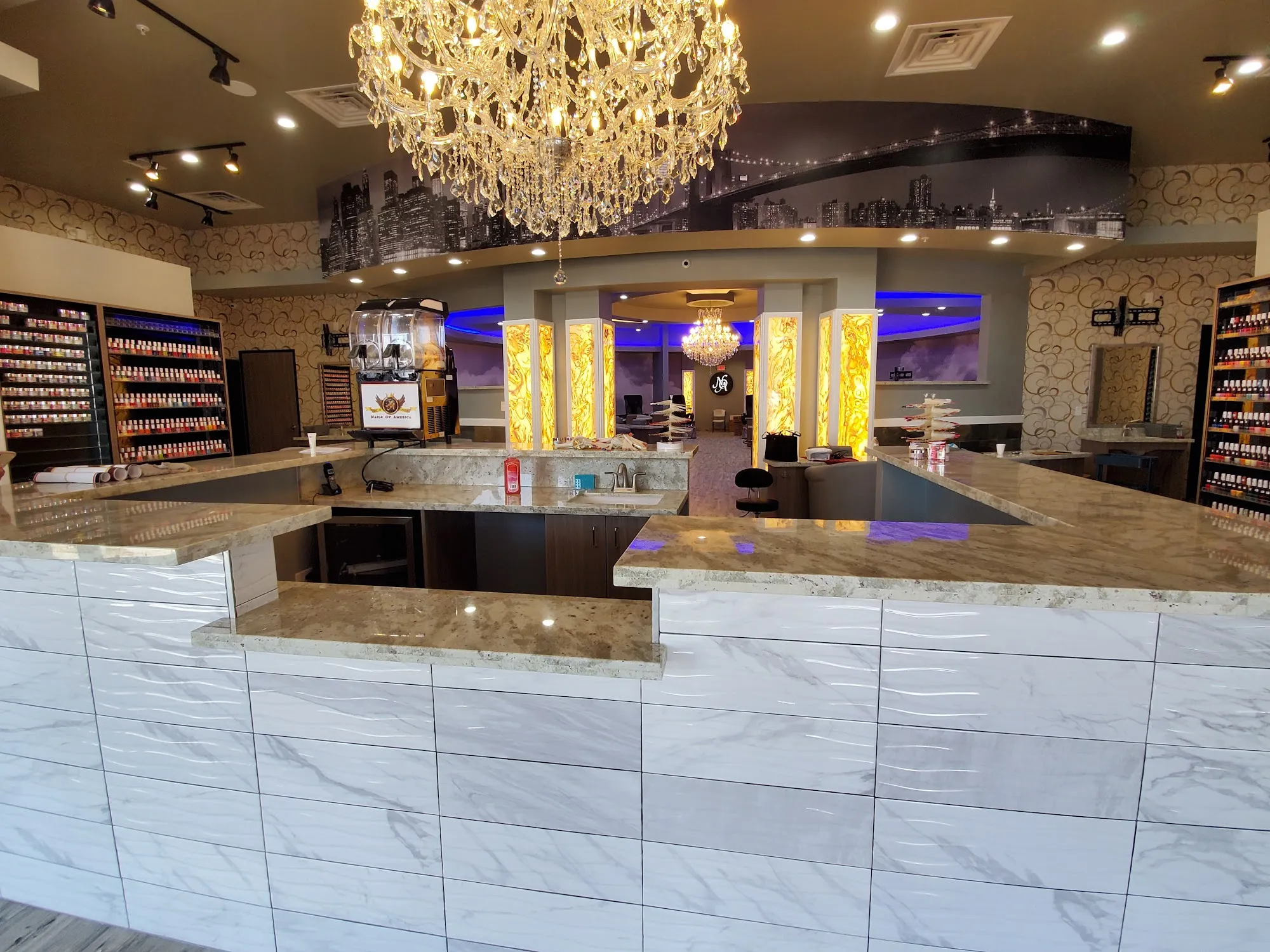 Polished marble reception desk and crystal chandelier inside Nails of America Meyerland